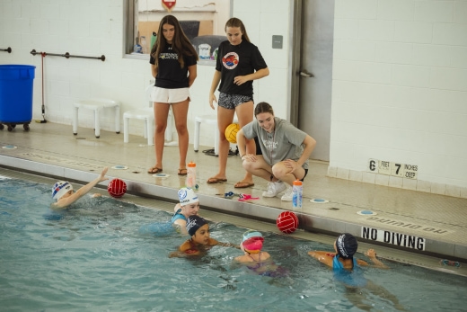 coach talking to water polo teen girls team in water